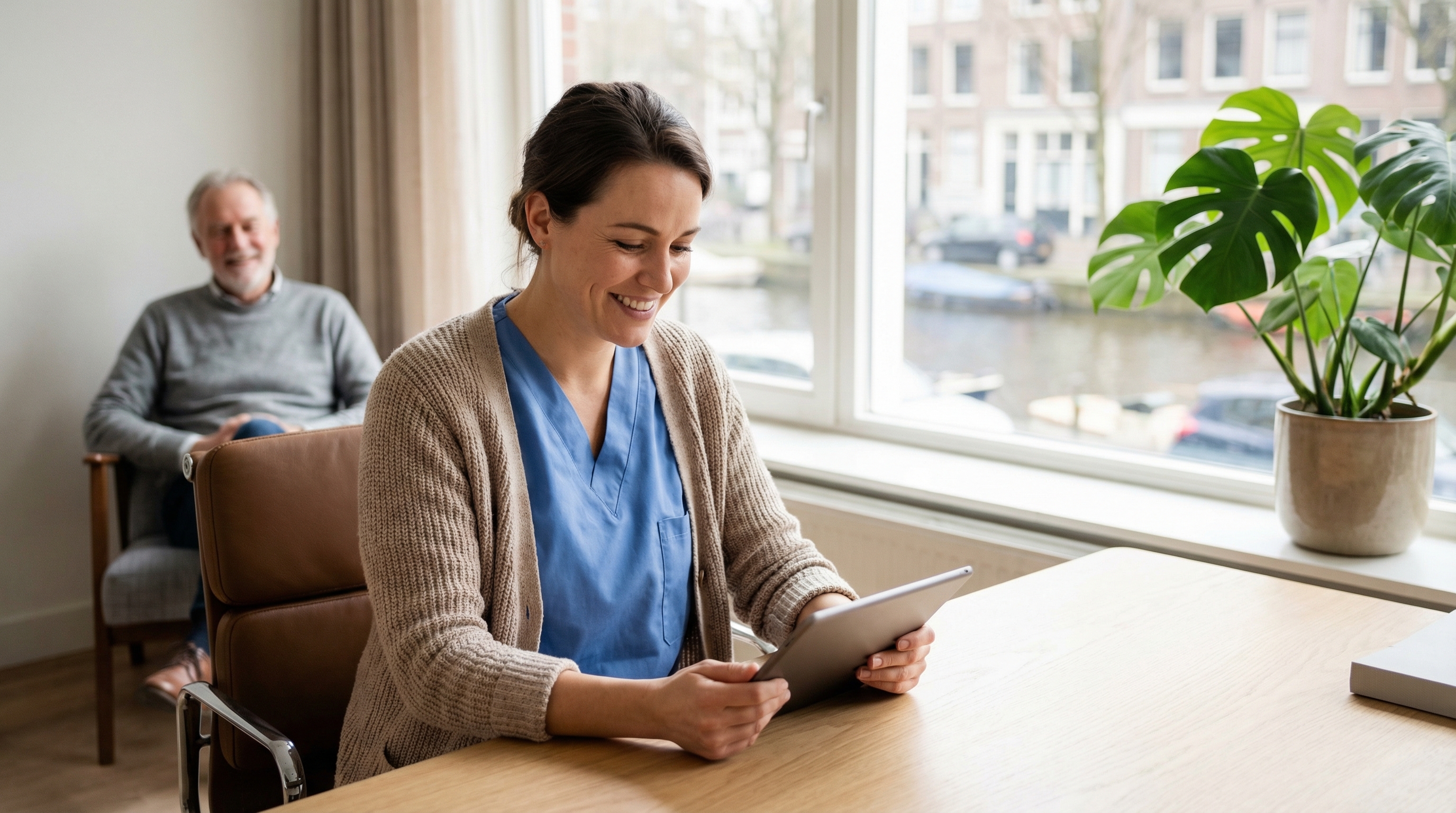 Physician Assistant bij Amsta Amsterdam werkt met tablet, uitzicht op Amsterdams kanaal